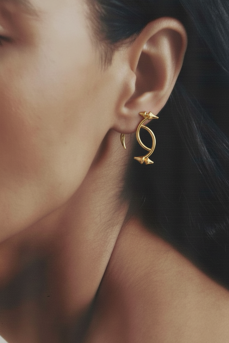 Close-up of a person wearing gold earrings with a blurred background